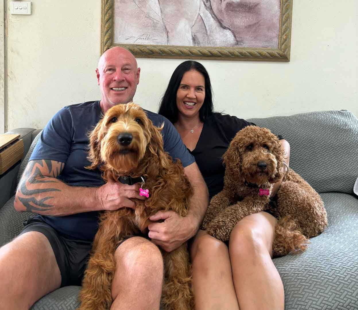 Groodles of Noosa owners, Laura & Clint, sitting on couch with two Groodles